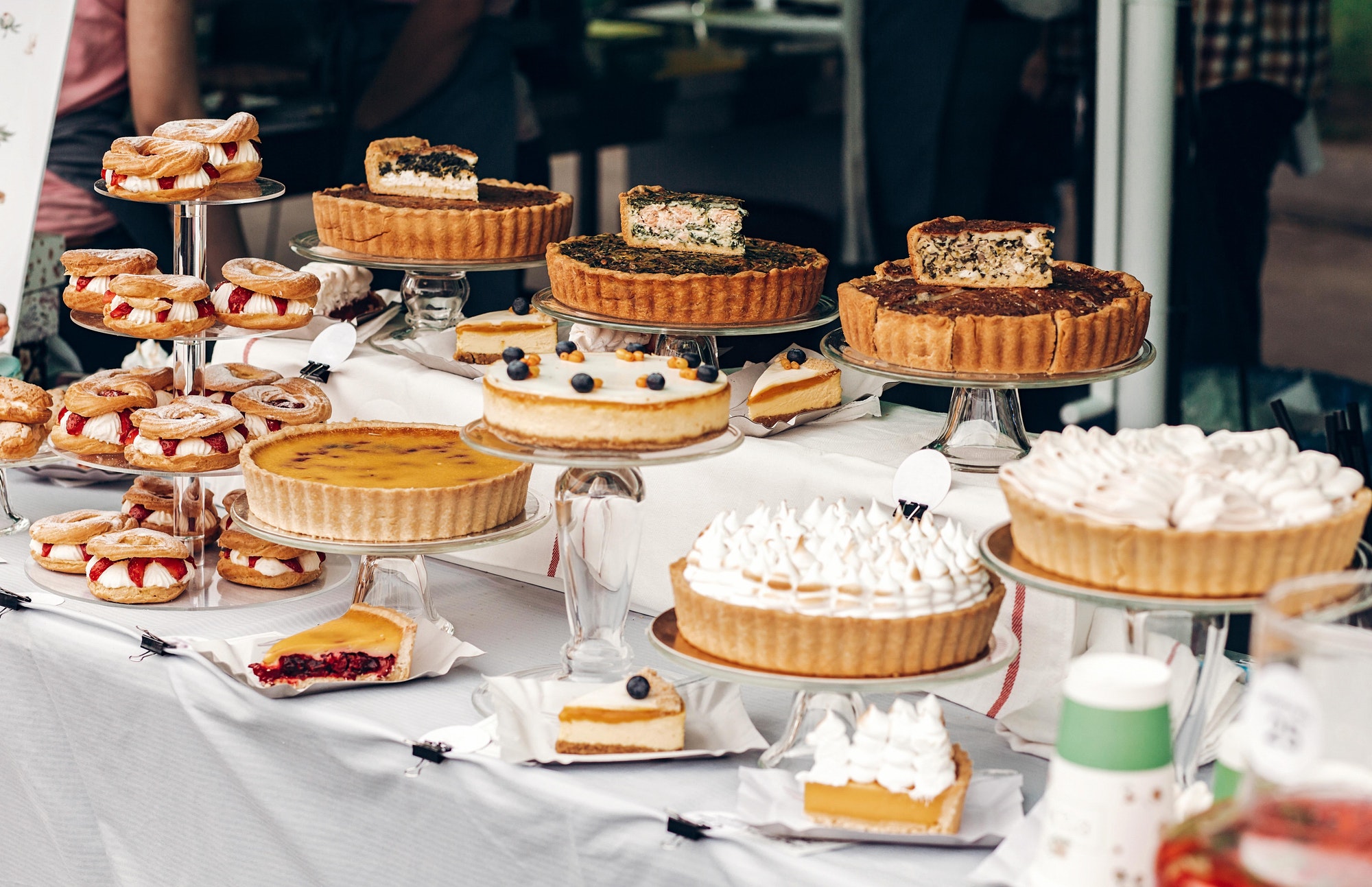 Delicious cakes and pie with whipped cream on table at street food festival